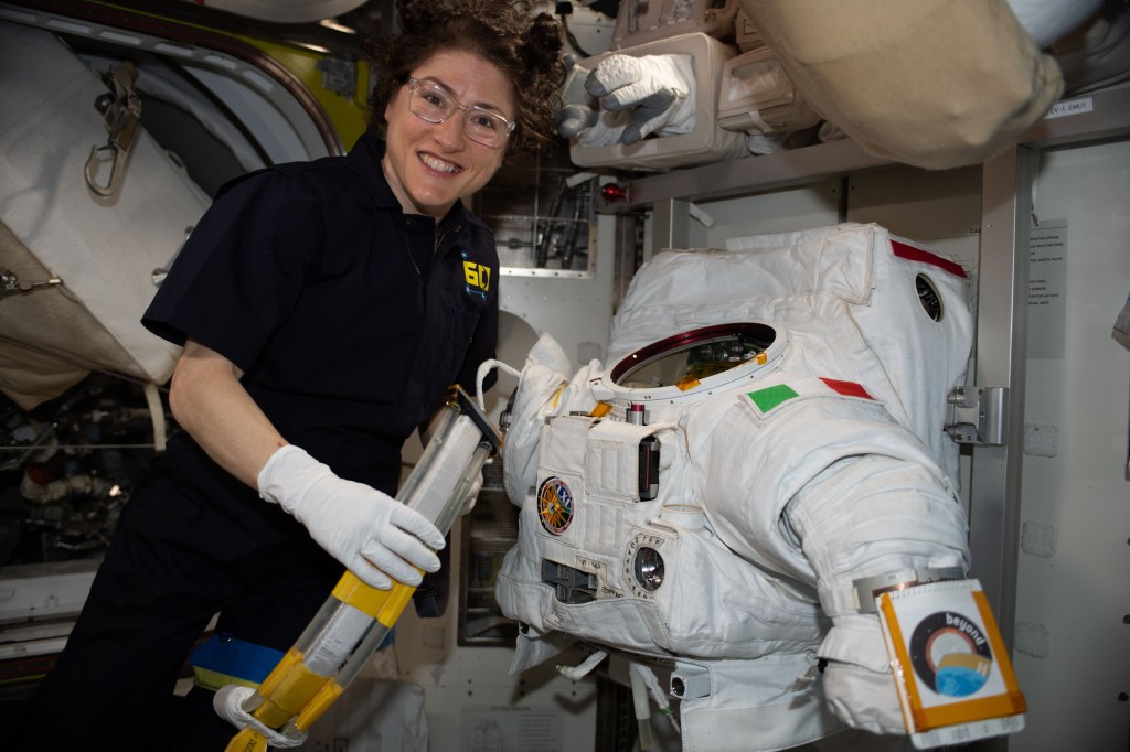 NASA astronaut Christina Koch works on a U.S. spacesuit, with a patch of the Italian flag on the left shoulder, that Commander Luca Parmitano of ESA (European Space Agency) wore during a spacewalk on Dec. 2, 2019.
