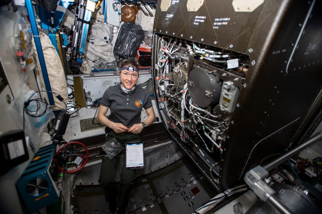 NASA astronaut Christina Koch works on orbital plumbing tasks as she replaces components inside the International Space Station's bathroom, the Waste and Hygiene Compartment, located in the Tranquility module.