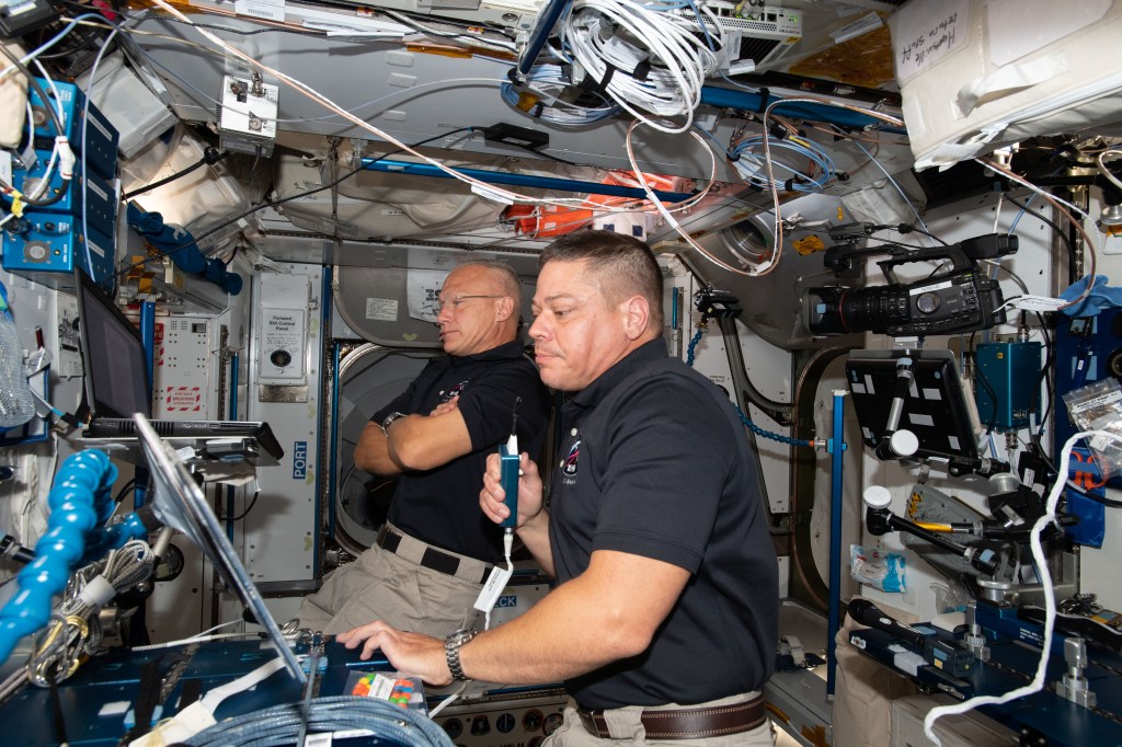NASA astronauts Bob Behnken (foreground) and Doug Hurley, who flew the Crew Dragon spacecraft to the International Space Station during SpaceX Demonstration Mission-2, are pictured briefing mission controllers about their experience in the new vehicle.