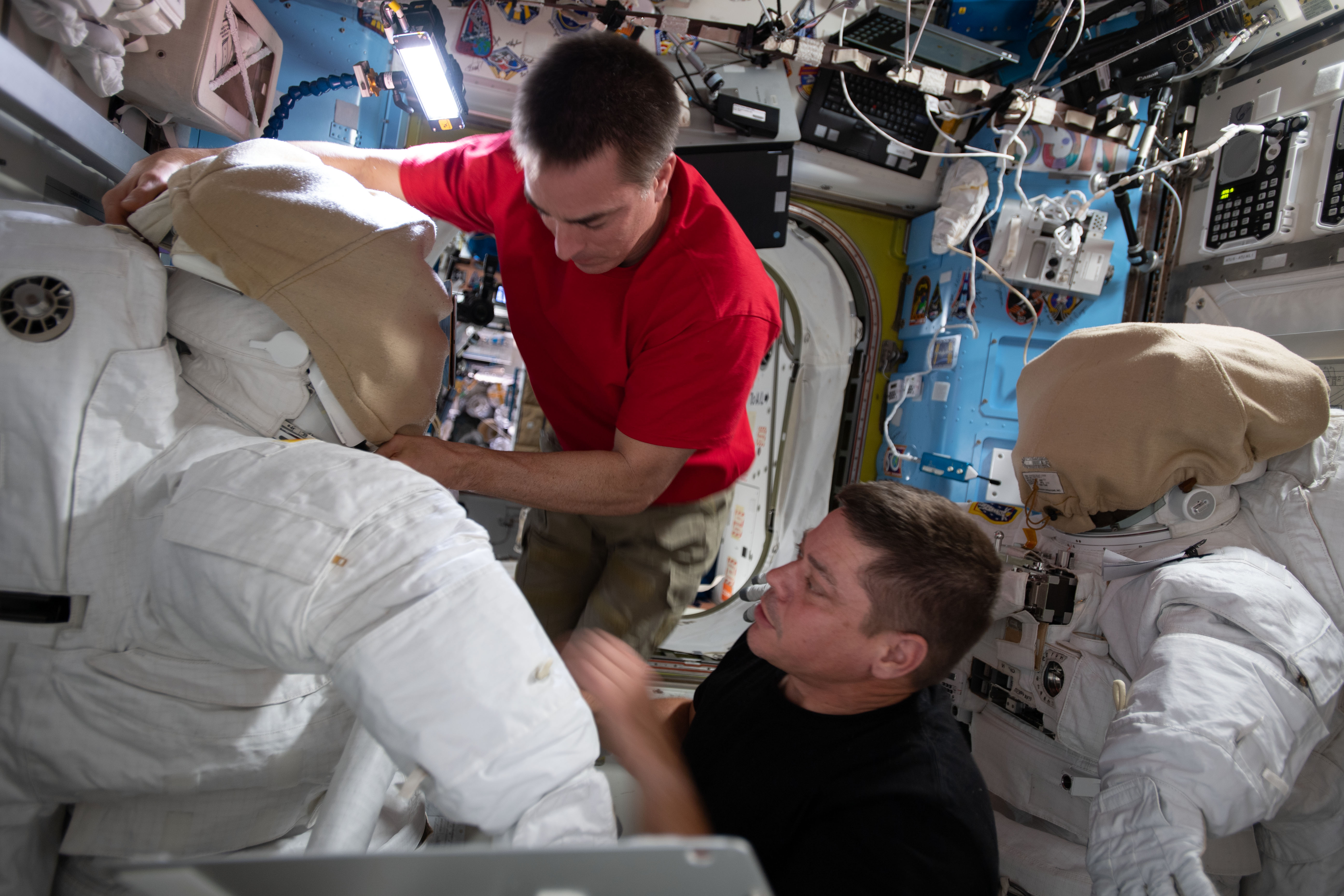 NASA astronauts (from top) Chris Cassidy and Bob Behnken work on U.S. spacesuits inside the International Space Station's Quest airlock.