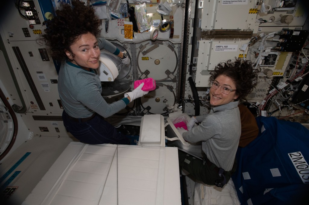 NASA astronauts (from left) Jessica Meir and Christina Koch work inside the Kibo laboratory module collecting frozen biological samples for stowage inside the SpaceX Dragon resupply ship. Dragon parachuted to a splashdown in the Pacific Ocean the following day on Jan. 7, 2020.