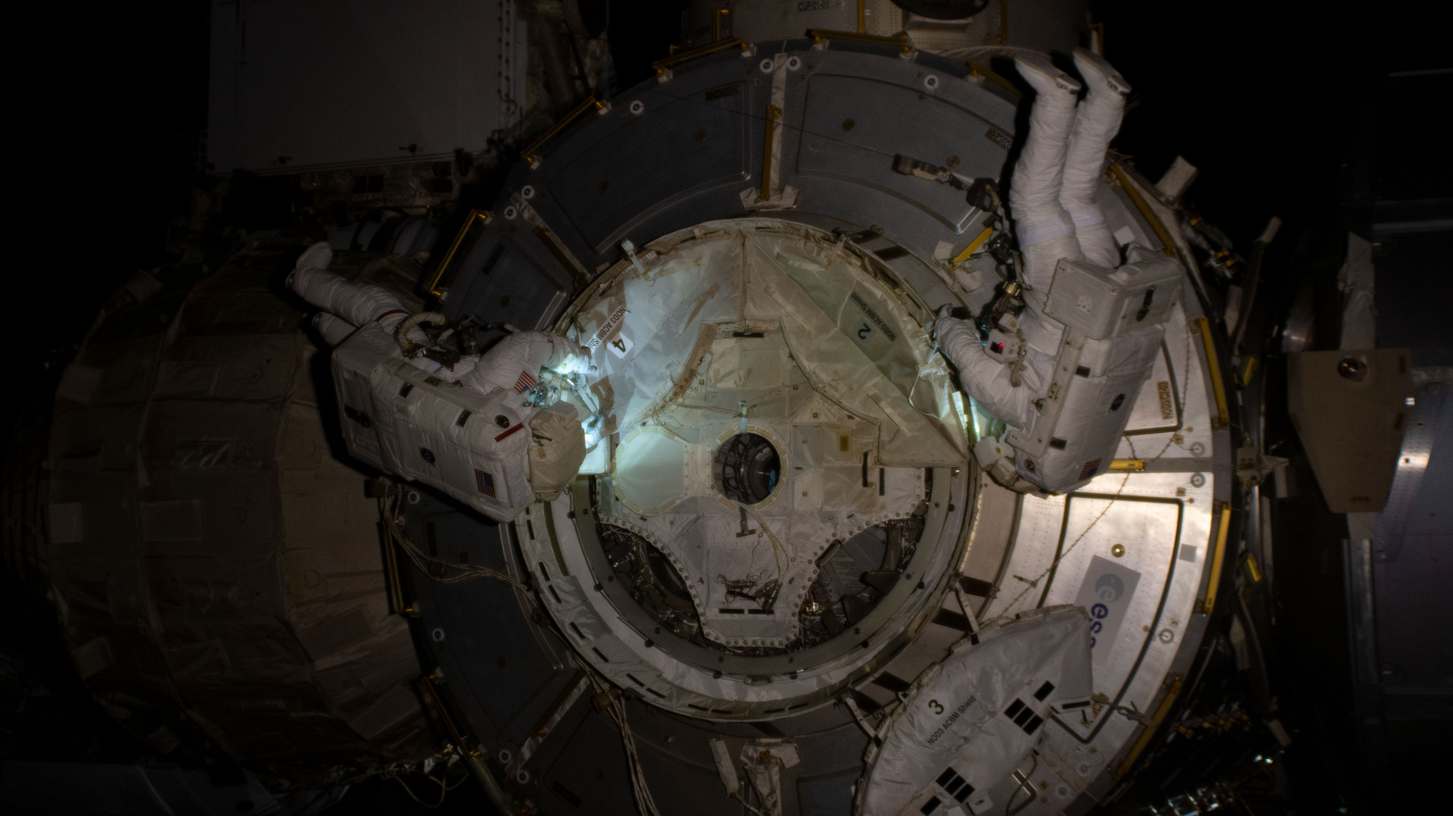 NASA spacewalkers (from left) Bob Behnken and Chris Cassidy set up the outside of the Tranquility module for the future installation of the NanoRacks airlock.