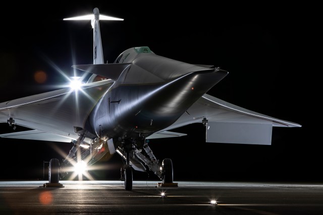 NASA's X-59 airplane sits on the ground with lights shining on it.