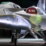 NASA's X-59 airplane sits in its hangar with lights shining on it.
