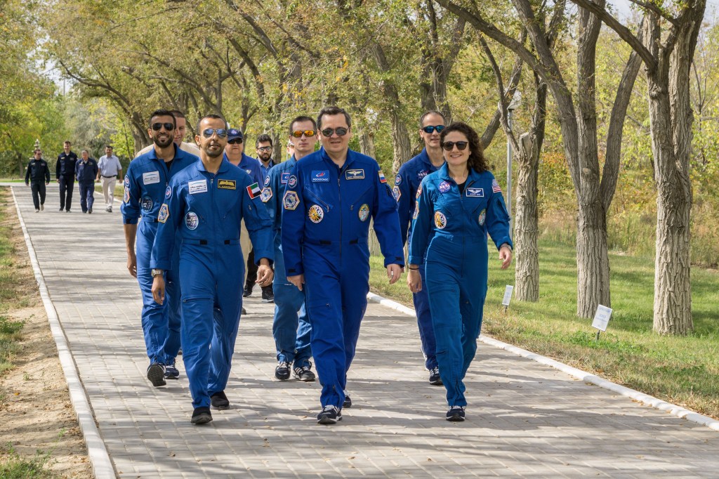 At the Cosmonaut Hotel crew quarters in Baikonur, Kazakhstan, spaceflight participant Hazzaa Ali Almansoori of the United Arab Emirates (left), Oleg Skripochka of Roscosmos (center) and Jessica Meir of NASA (right) lead the way down the Walk of Cosmonauts Sept. 18 as part of pre-launch activities. They will launch Sept. 25 from the Baikonur Cosmodrome in Kazakhstan on the Soyuz MS-15 spacecraft for a mission on the International Space Station.