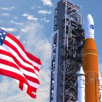 American flag waving in the wind on the left side, slightly in front of a orange and white space shuttle pointed toward the sky.