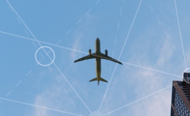 Underside of an airplane flying in a blue sky with lines drawn on to indicate air traffic patterns