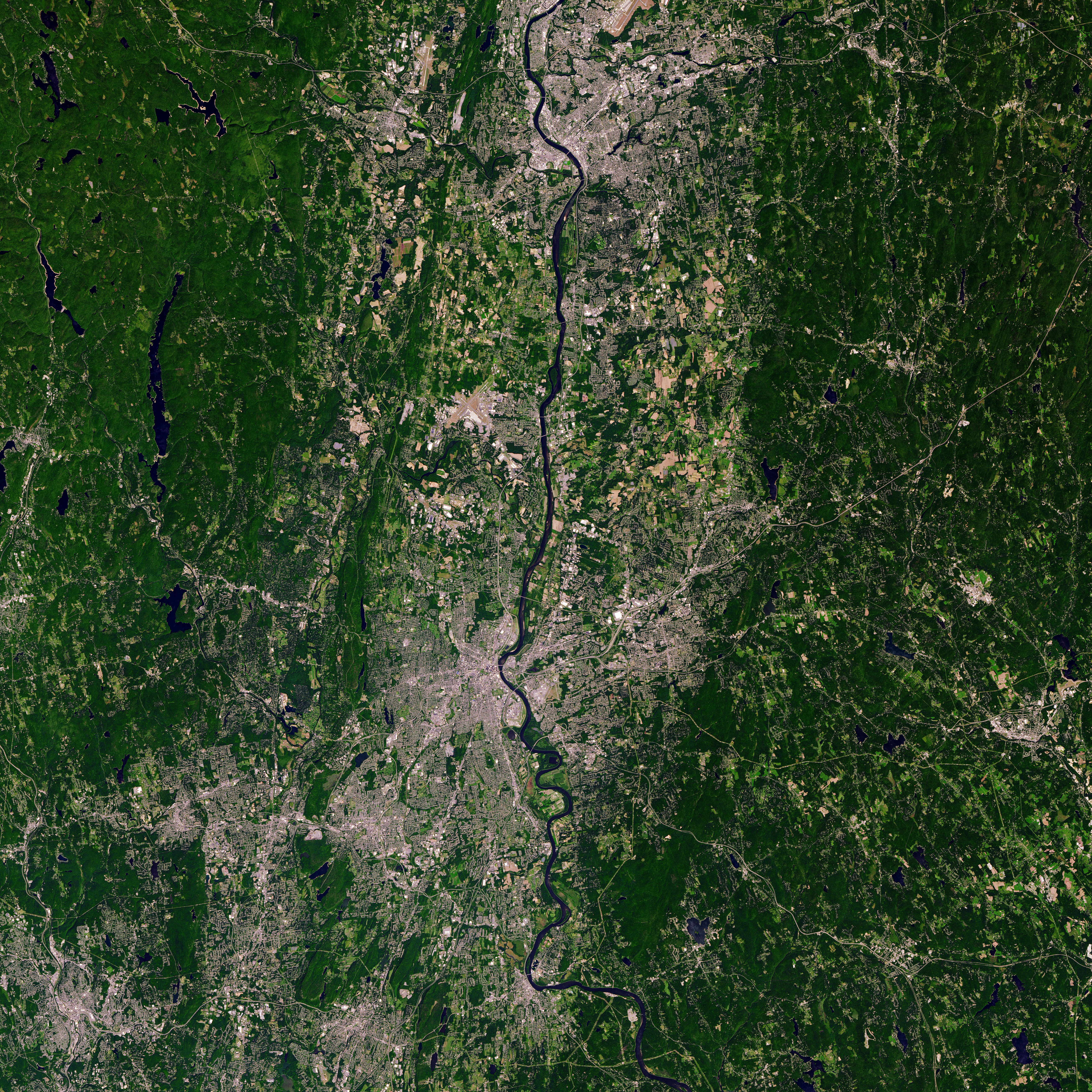 A view of Simsbury, Connecticut from the Landsat 9 satellite. The edges of the image are green, while the center has patches of brown along a water source.