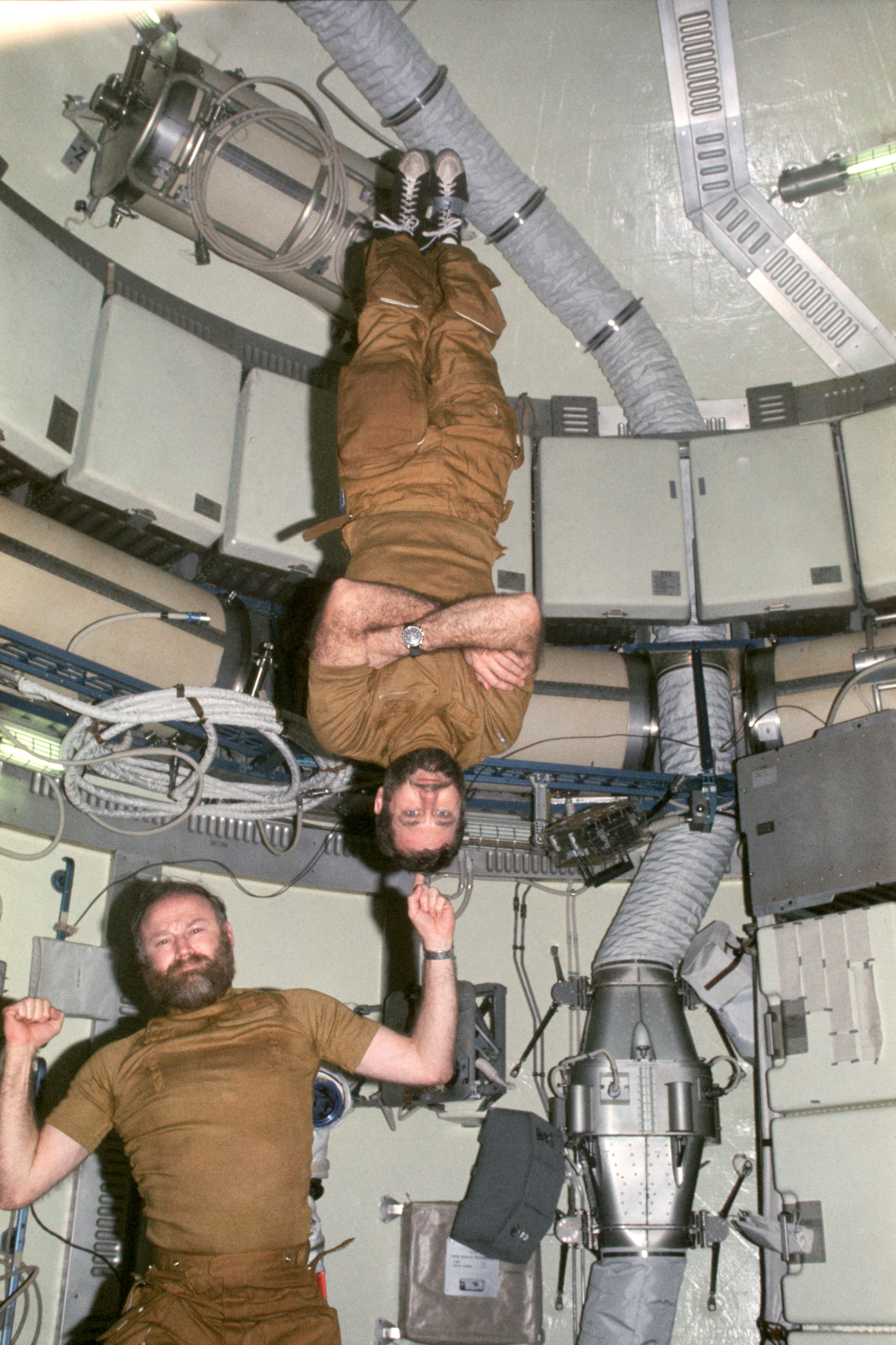 Carr demonstrates his strength in weightlessness by “supporting” William R. Pogue on one finger