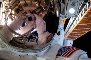A spacewalker's spacesuit gloves and camera are reflected in the helmet visor in this "space-selfie" taken during a six-hour and seven-minute spacewalk.