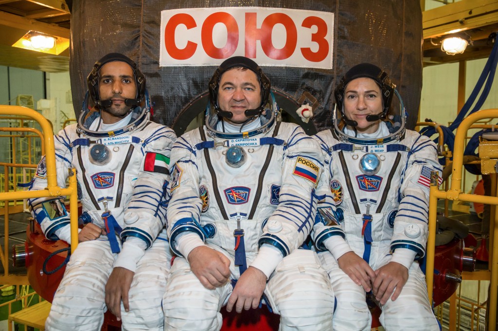 In the Integration Building at the Baikonur Cosmodrome in Kazakhstan, spaceflight participant Hazzaa Ali Almansoori of the United Arab Emirates (left) and Expedition 61 crewmates Oleg Skripochka of Roscosmos (center) and Jessica Meir of NASA (right) pose for pictures Sept. 11 in front of their Soyuz MS-15 spacecraft. They will launch Sept. 25 on the Soyuz MS-15 spacecraft from the Baikonur Cosmodrome for a mission on the International Space Station.