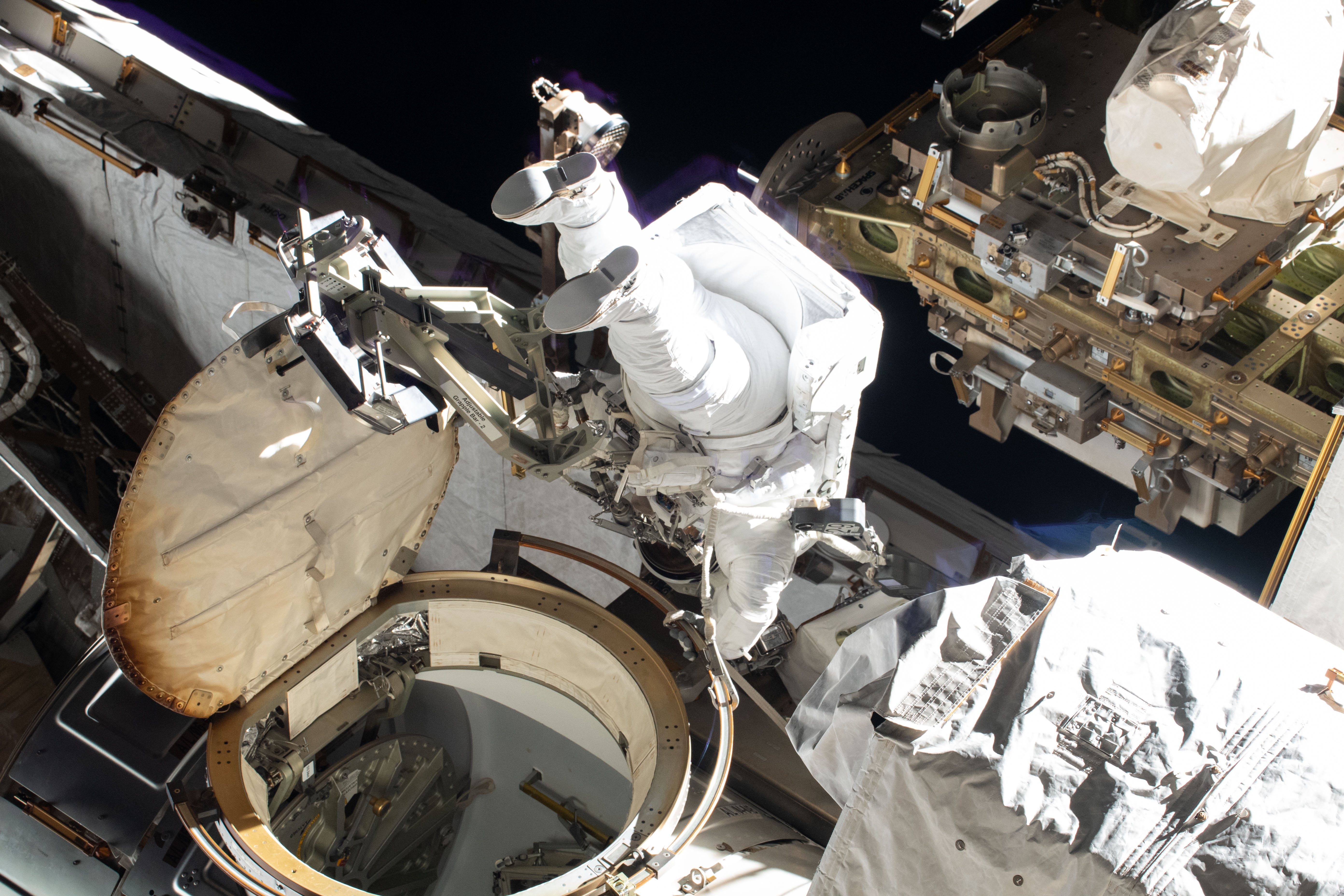 Spacewalker and NASA astronaut Christina Koch exits the Quest airlock shortly after setting her U.S. spacesuit to battery power beginning her first spacewalk to upgrade the International Space Station's power storage capacity. She and fellow spacewalker Nick Hague (out of frame) of NASA worked outside in the vacuum of space for six hours and 45 minutes to continue swapping batteries and install adapter plates on the station's Port-4 truss structure.