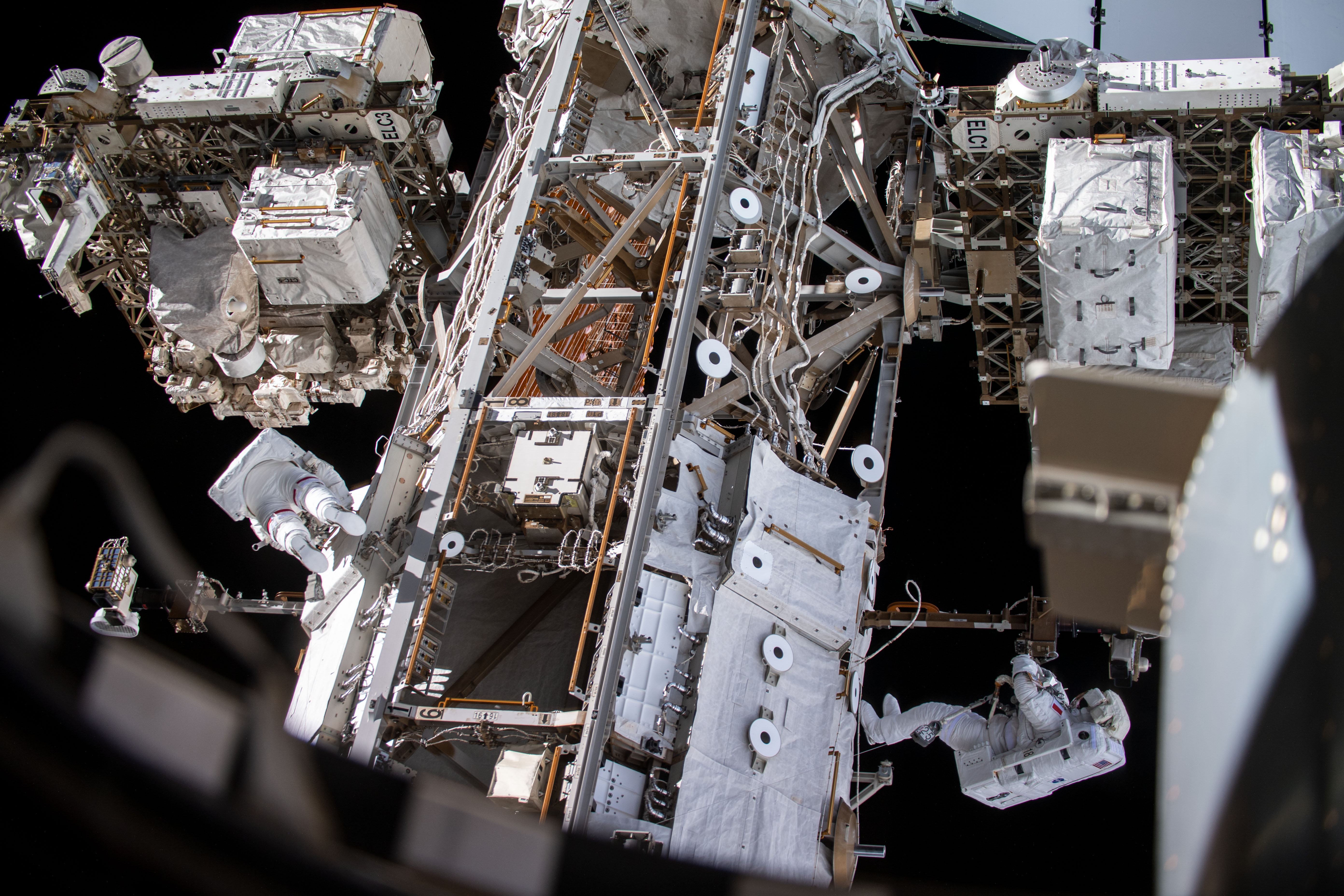 Spacewalkers Andrew Morgan (left) and Luca Parmitano (bottom right) work on get-ahead tasks after completing thermal repairs on the Alpha Magnetic Spectrometer, a dark matter and antimatter detector.