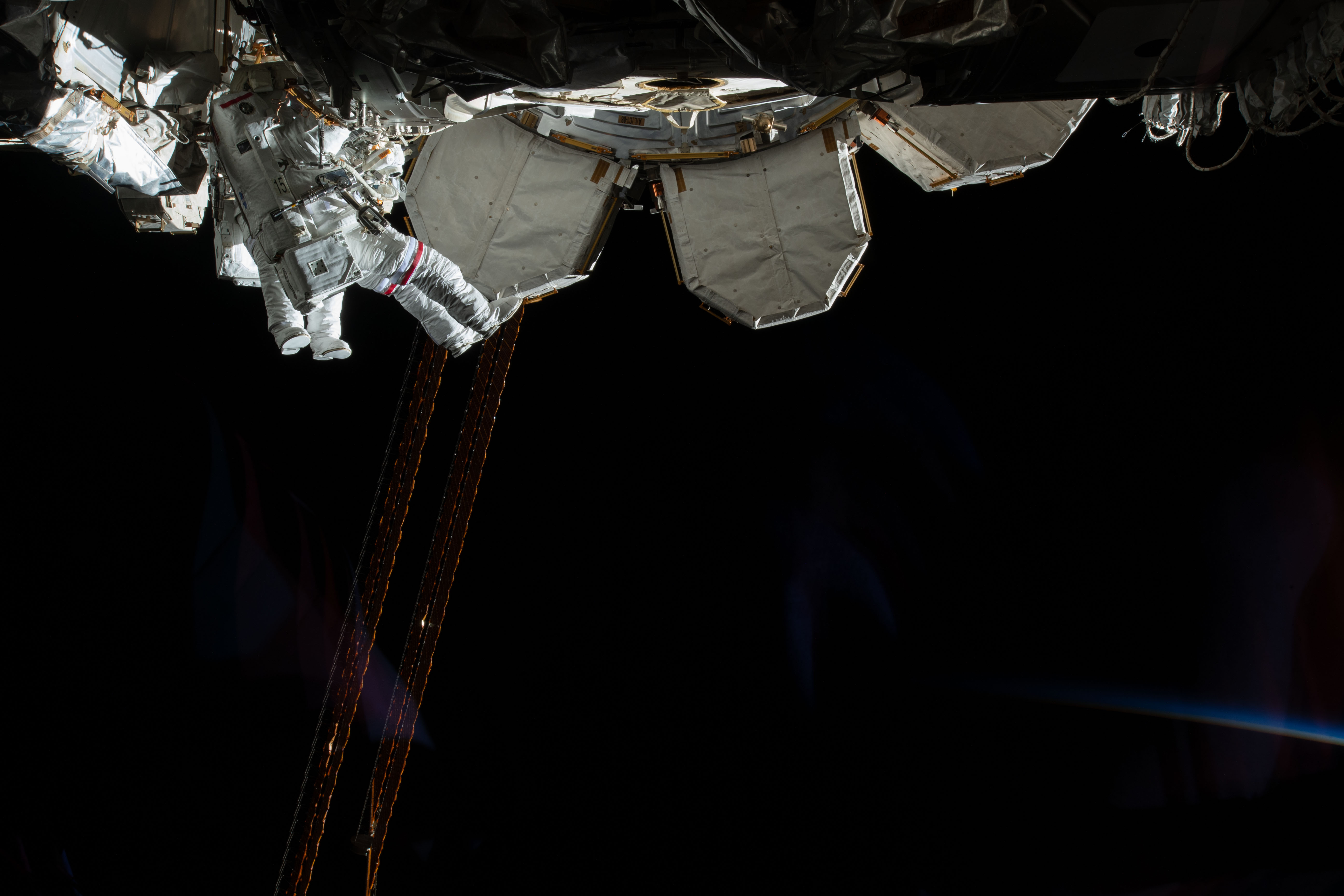Expedition 59 Flight Engineers Anne McClain of NASA (red stripes) and David Saint-Jacques of the Canadian Space Agency are seen while working outside the International Space Station. In a six and a half hour spacewalk, McClain and Saint-Jacques successfully established a redundant path of power to the Canadian-built robotic arm, known as Canadarm2, and installed cables to provide for more expansive wireless communications coverage outside the orbital complex, as well as for enhanced hardwired computer network capability. The duo also relocated an adapter plate from the first spacewalk in preparation for future battery upgrade operations.