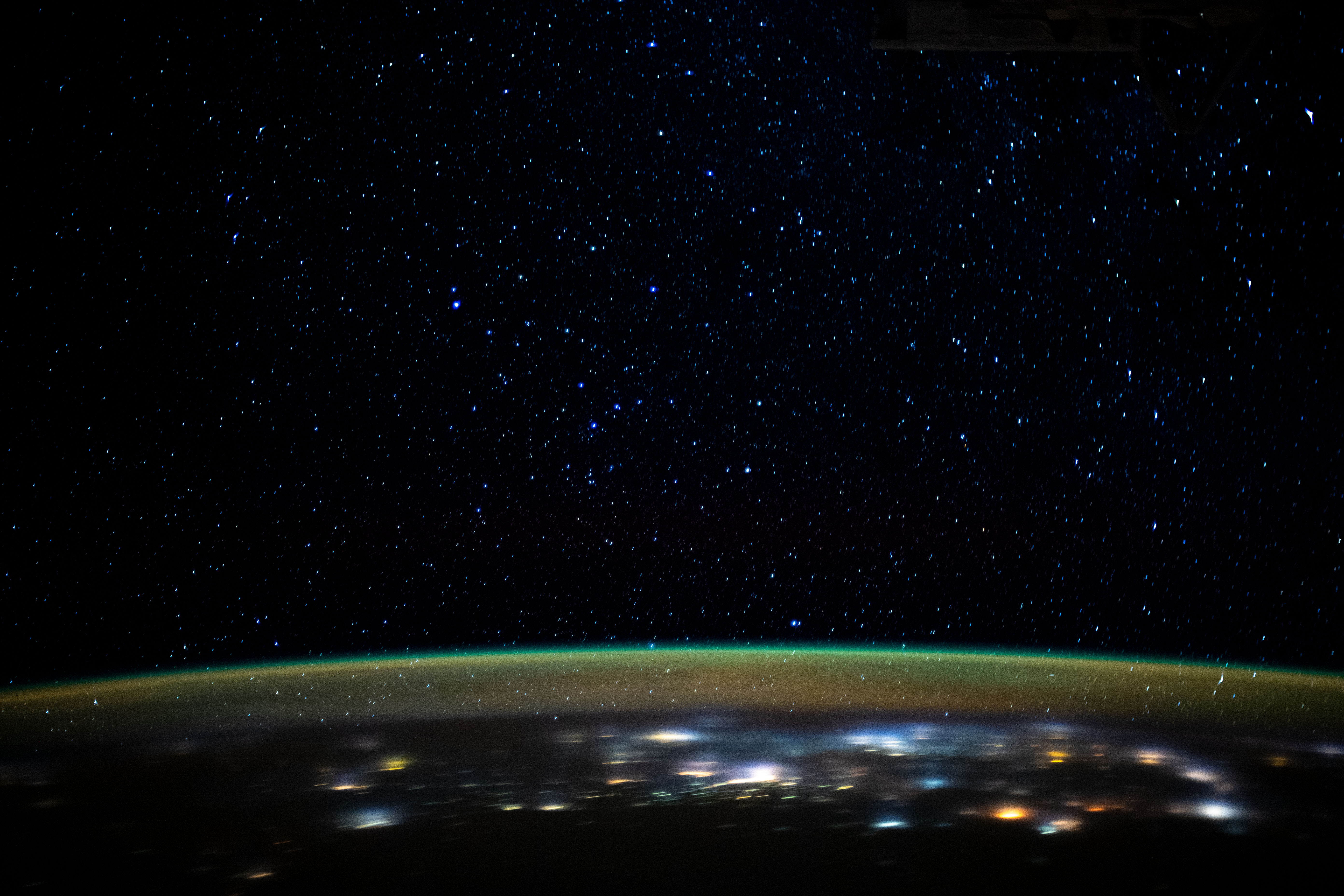 Stars glitter in the night sky above an atmospheric glow that blankets the city lights as the International Space Station orbited 260 miles above northern Iran as it was about to cross the Caspian Sea.