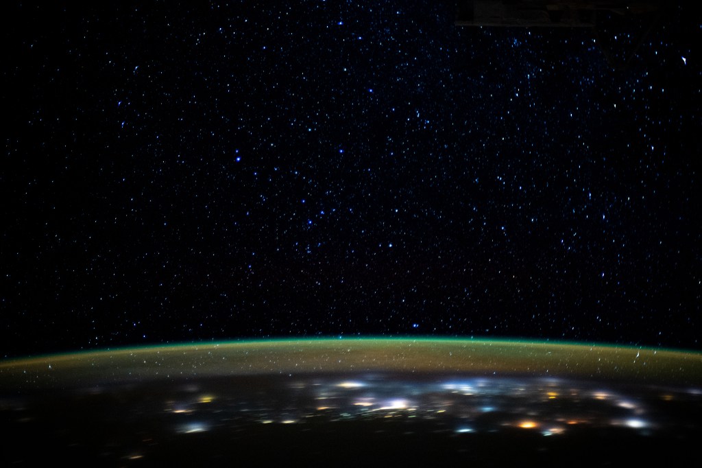 Stars glitter in the night sky above an atmospheric glow that blankets the city lights as the International Space Station orbited 260 miles above northern Iran as it was about to cross the Caspian Sea.