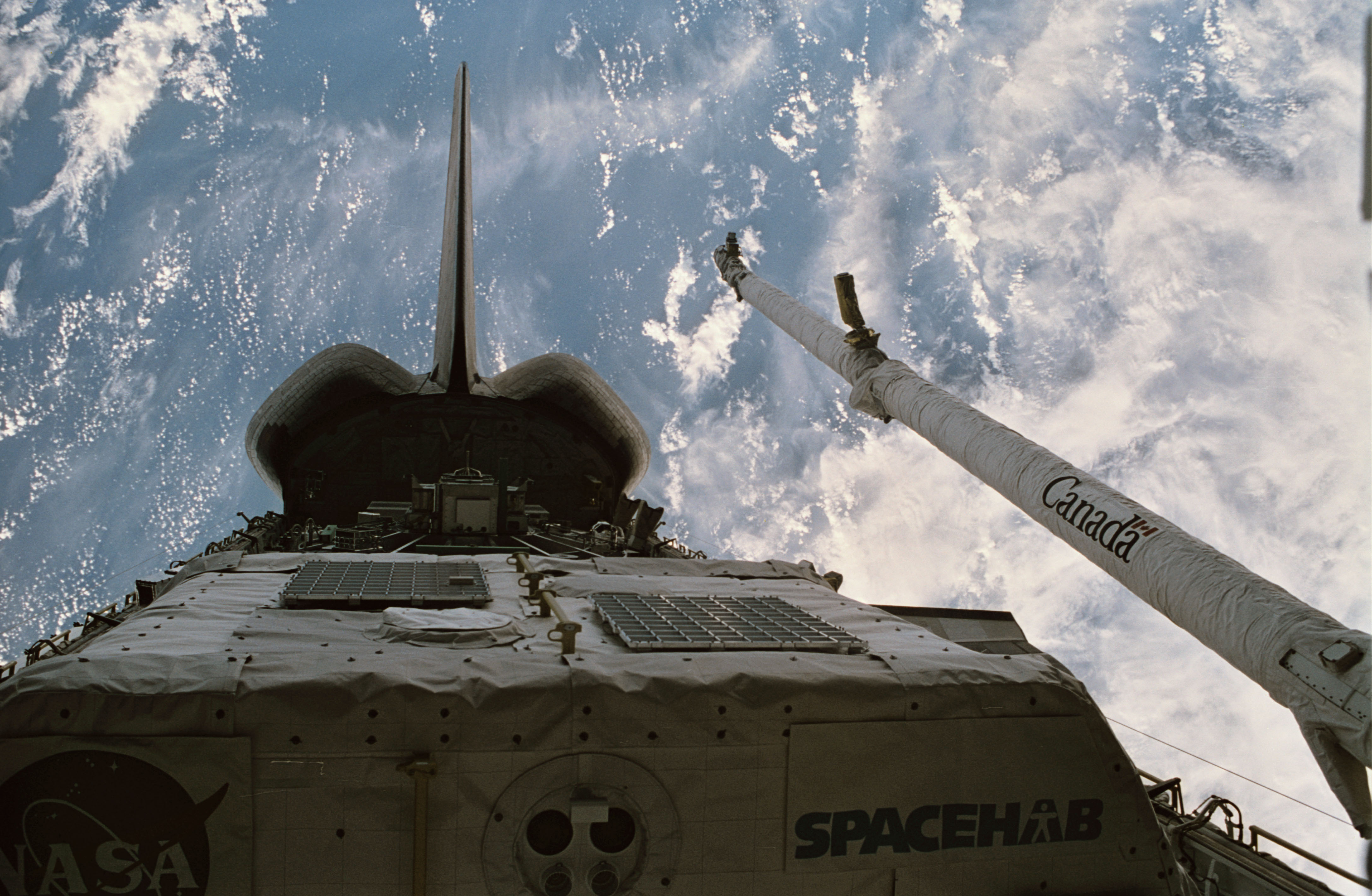 Discovery’s payload bay, showing the Spacehab module including the externally mounted Sample Return Experiment, and the Canadian-built Remote Manipulator System