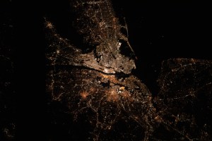 The bright city lights of Long Island, New York City and the New Jersey area contrast the dark waters of Sandy Hook Bay, the Upper and Lower Bays, the Hudson and East Rivers and Long Island Sound, that surround the major metropolitan area of the northeastern United States.