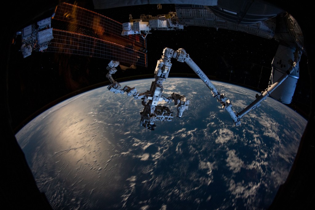 The Canadarm2 robotic arm with the Dextre robotic hand attached seemingly protrudes from the side of the International Space Station as the orbiting complex soared 263 miles above the South Pacific Ocean.