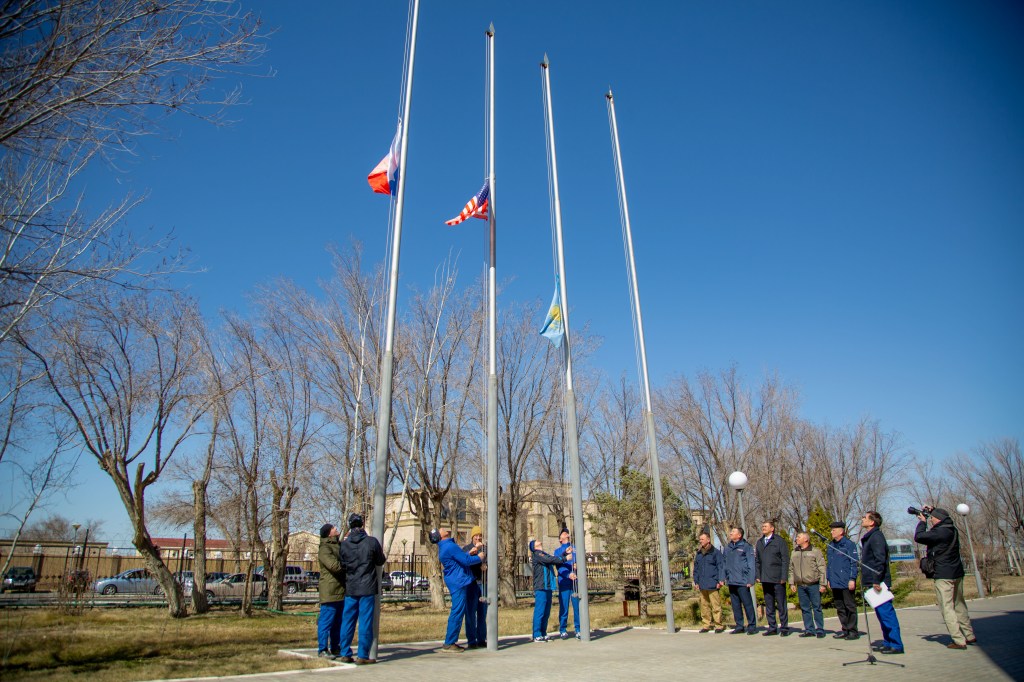 At the Cosmonaut Hotel crew quarters in Baikonur, Kazakhstan, the Expedition 63 prime and backup crewmembers raise the Russian, U.S. and Kazakh flags March 26 in a traditional ceremony. From left to right are prime crewmembers Ivan Vagner and Anatoly Ivanishin of Roscosmos, prime crewmember Chris Cassidy of NASA and his backup, Steve Bowen of NASA and backup crewmembers Sergey Ryzhikov and Andrei Babkin. Cassidy, Ivanishin and Vagner will launch April 9 from the Baikonur Cosmodrome on the Soyuz MS-16 spacecraft for a six-and-a-half month mission on the International Space Station.