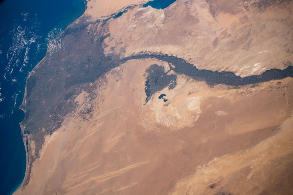 Looking like a leaf on a vine, the Faiyum Oasis extends west of the Nile River and south of Cairo, Egypt. The fertile area at the left of the photograph is the Nile Delta opening up into the Mediterranean Sea.