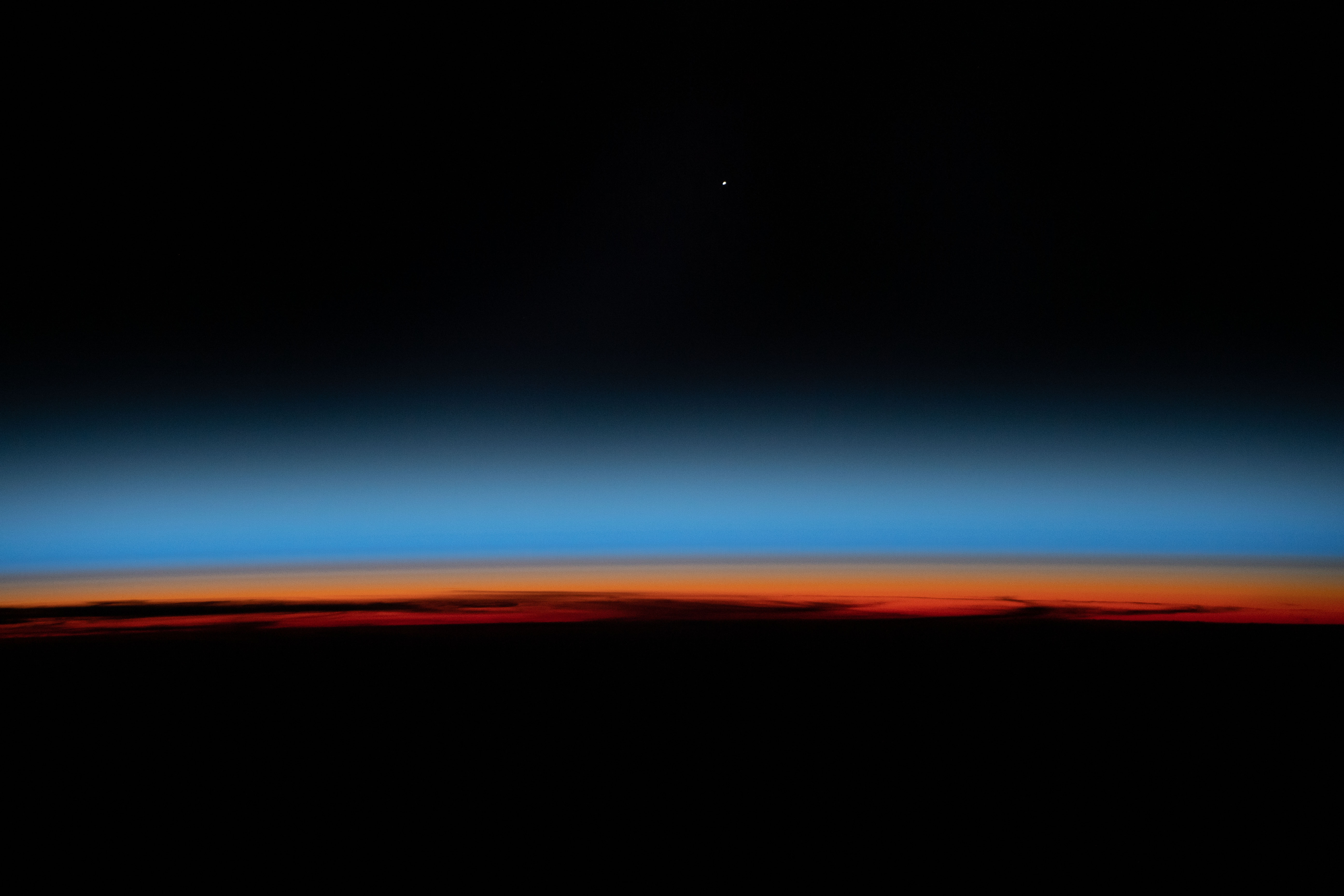 The first rays of an orbital sunrise shine illuminates the Earth's limb and highlights the atmosphere as the International Space Station orbits 259 miles above the central United States.