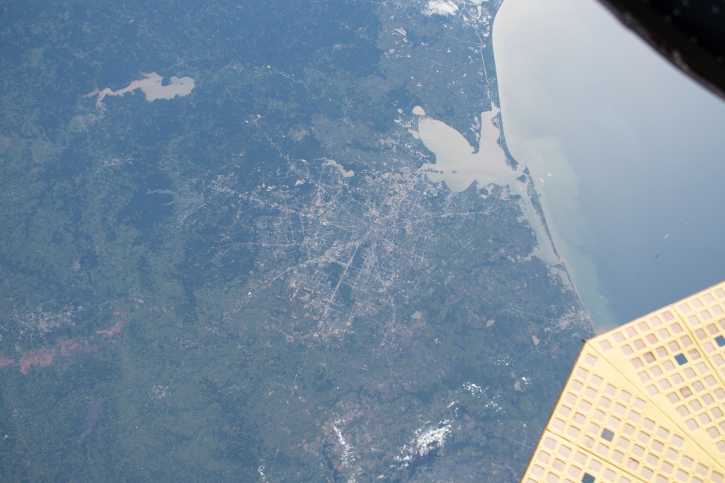 The Gulf of Mexico and Galveston Bay including Houston, Texas and its surrounding cities are pictured as the International Space Station orbited 256 miles above the Lone Star State. Lake Livingston and the Trinity River (upper left) are seen to the north of the Houston area. At lower right is a portion of one of two UltraFlex solar arrays that power Northrop Grumman's Cygnus cargo craft.