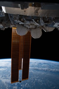 The International Space Station's main solar arrays drape across the Earth above the Pacific Ocean west of Hawaii.
