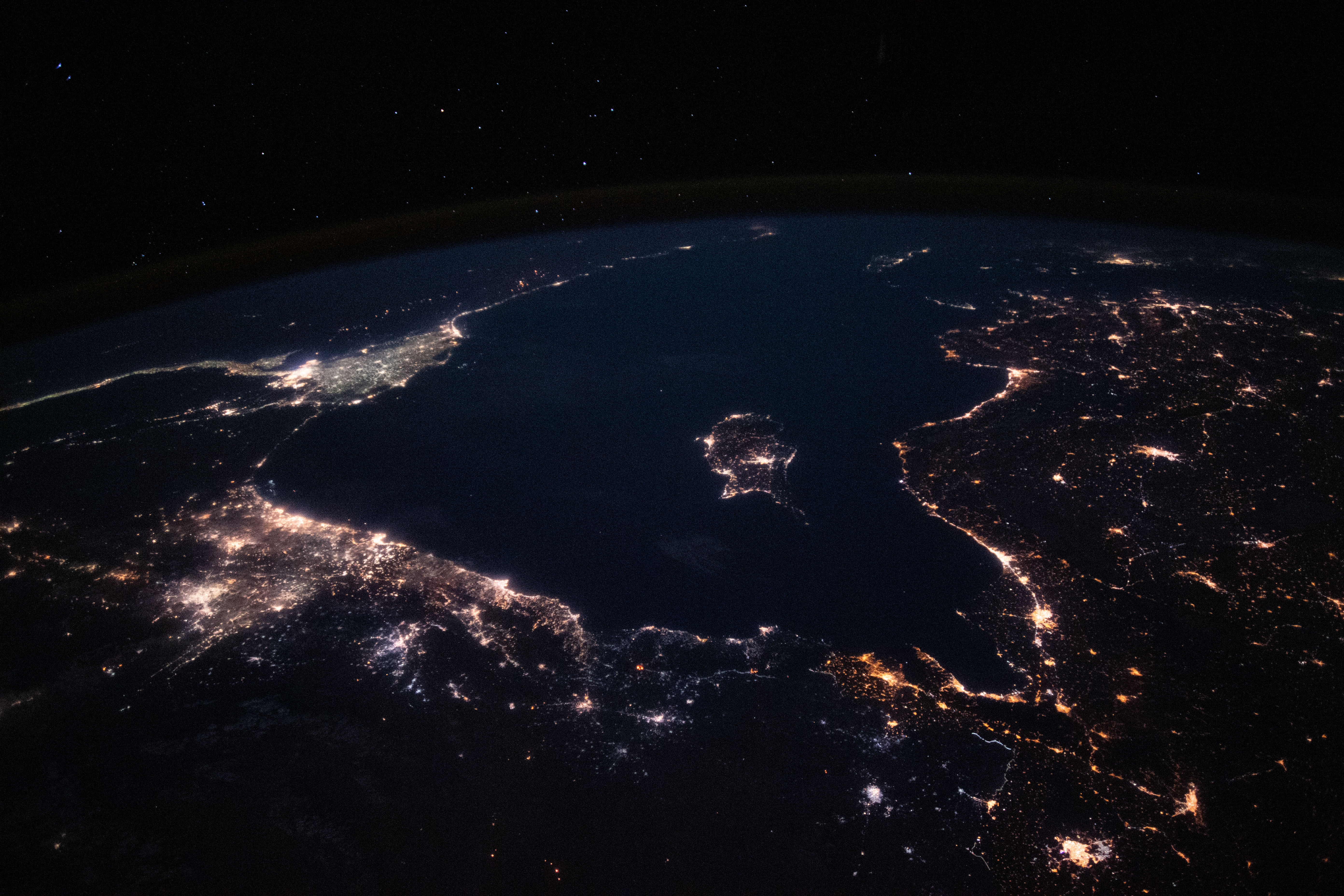 This nighttime view from the International Space Station looks across the Mediterranean Sea ringed by the coastal city lights of southeastern Europe, the Middle East and north Africa.