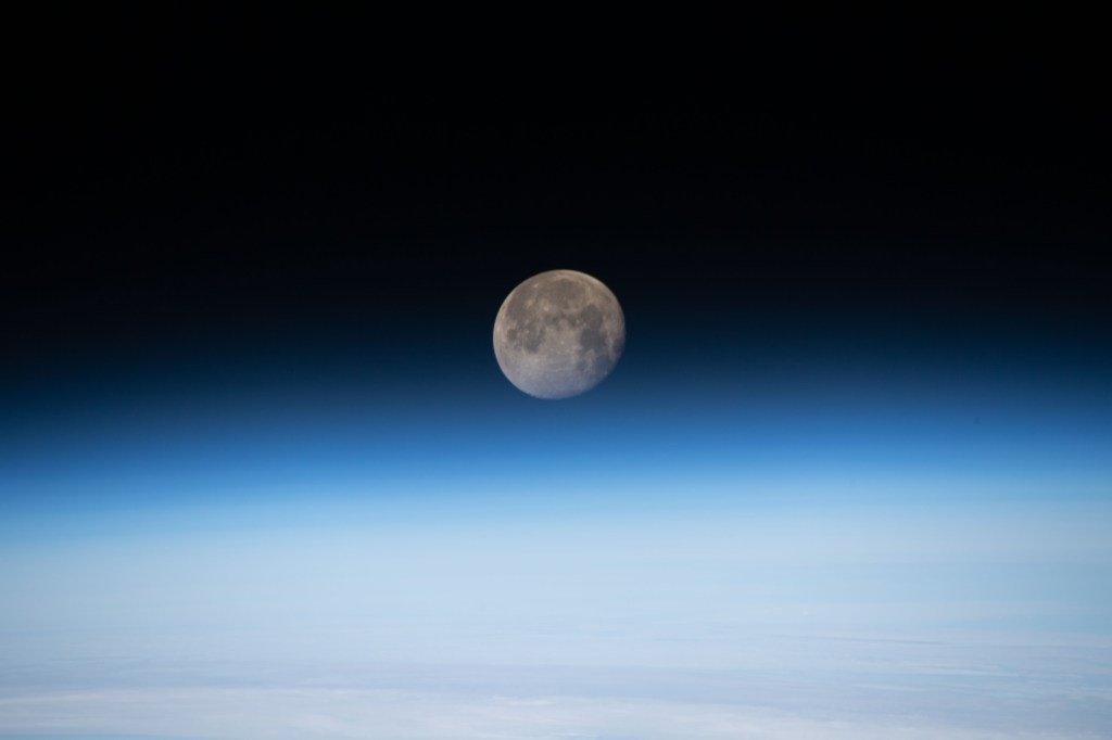 The moon is photographed in its waning gibbous phase just above the Earth's limb as the International Space Station orbited 258 miles above the North Atlantic Ocean just off the Canadian-American coast.