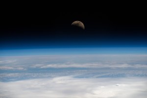 The moon is photographed in its first quarter phase just above the Earth's limb as the International Space Station orbited 255 miles above the Pacific Ocean south of the Hawaiian island chain.
