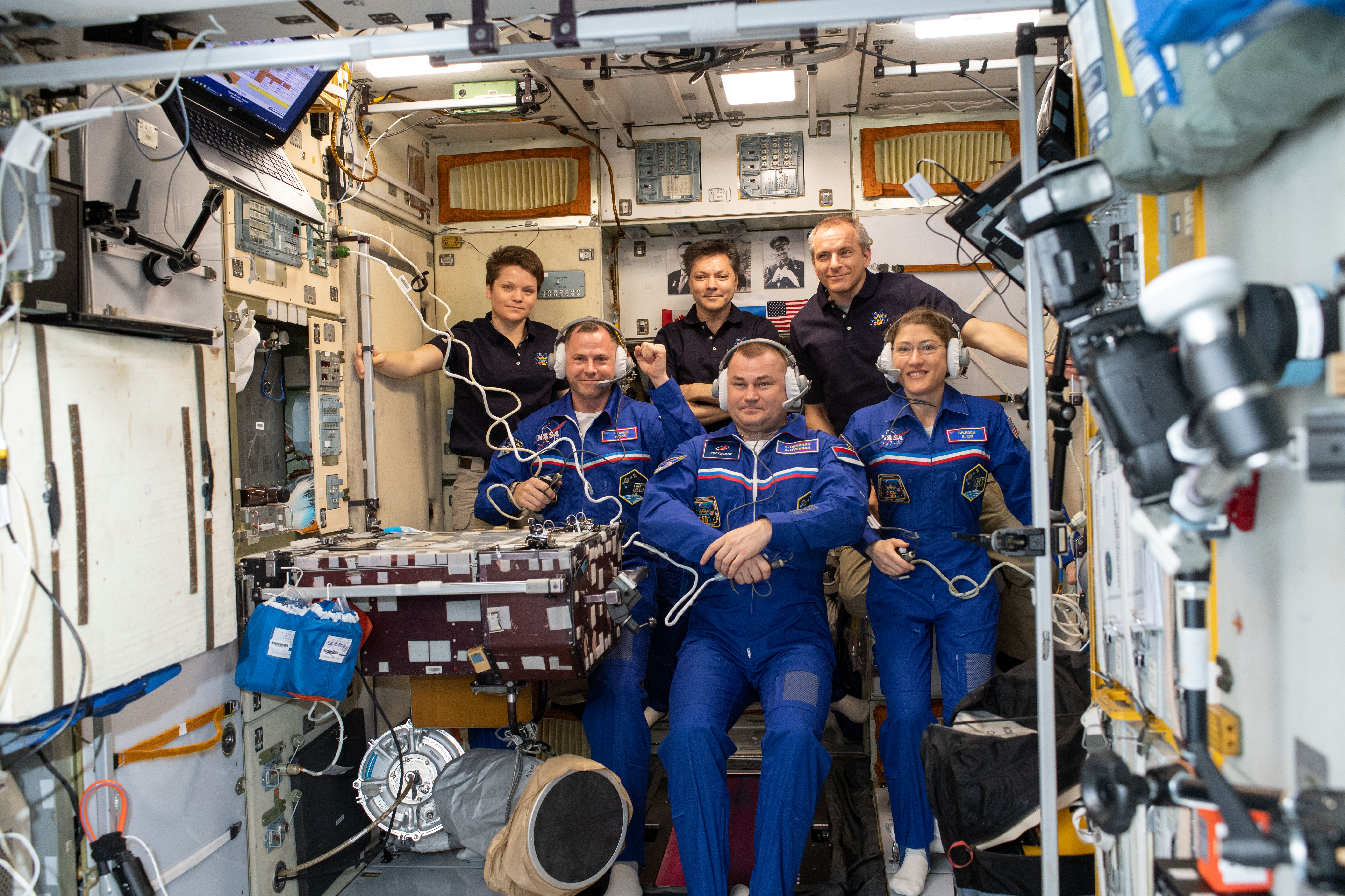 The newly-expanded Expedition 59 crew gathers inside the International Space Station's Zvezda service module as its three newest members speak with family, friends and mission officials who offered congratulations on a successful launch and docking. Front row, from left are new Flight Engineers Nick Hague, Alexey Ovchinin and Christina Koch. In the back, from left are Flight Engineer Anne McClain, Commander Oleg Kononenko and Flight Engineer David Saint-Jacques.