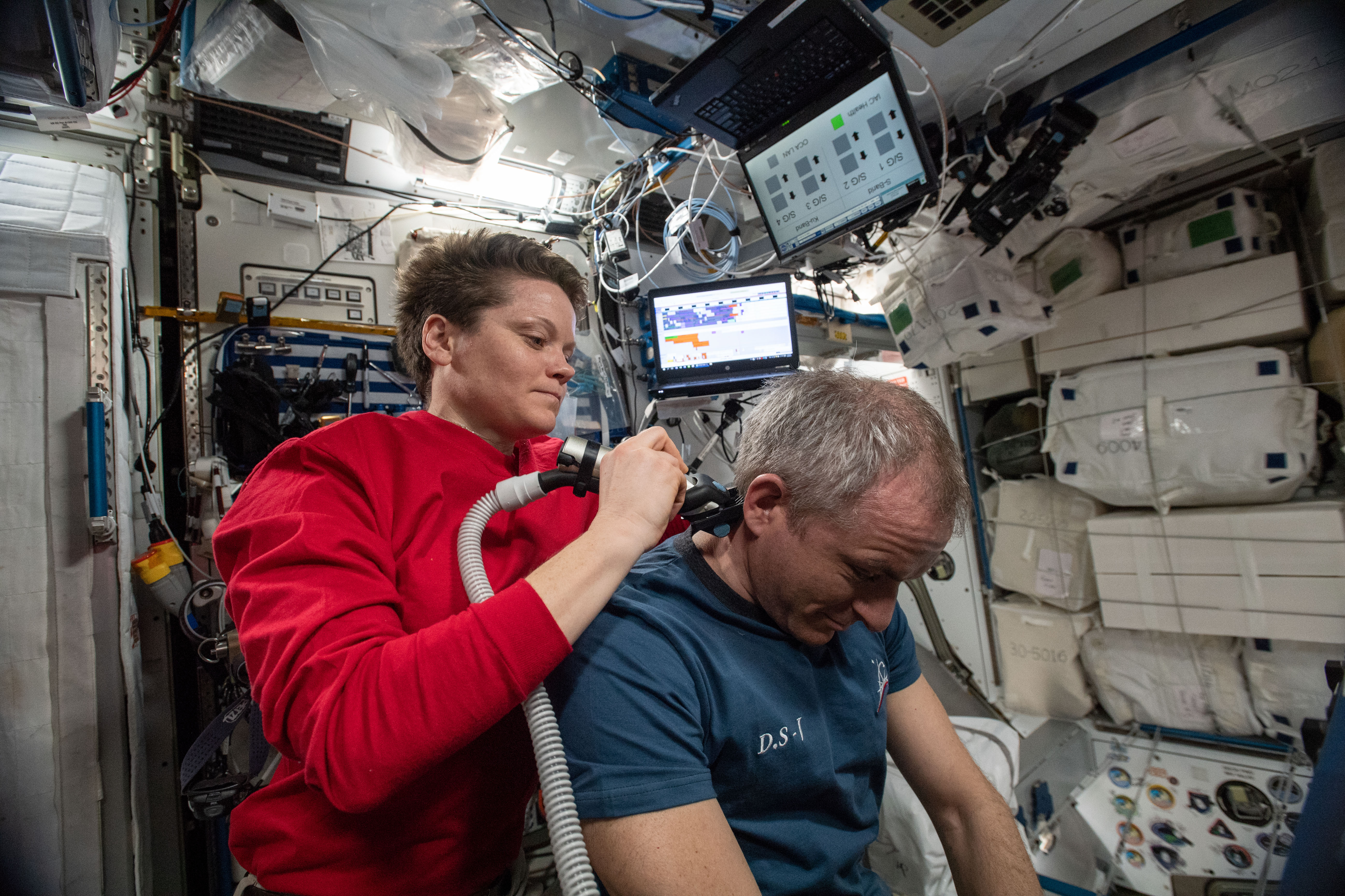 The orbital lab becomes a high-flying hair salon as NASA astronaut Anne McClain trims the hair of David Saint-Jacques of the Canadian Space Agency aboard the International Space Station.