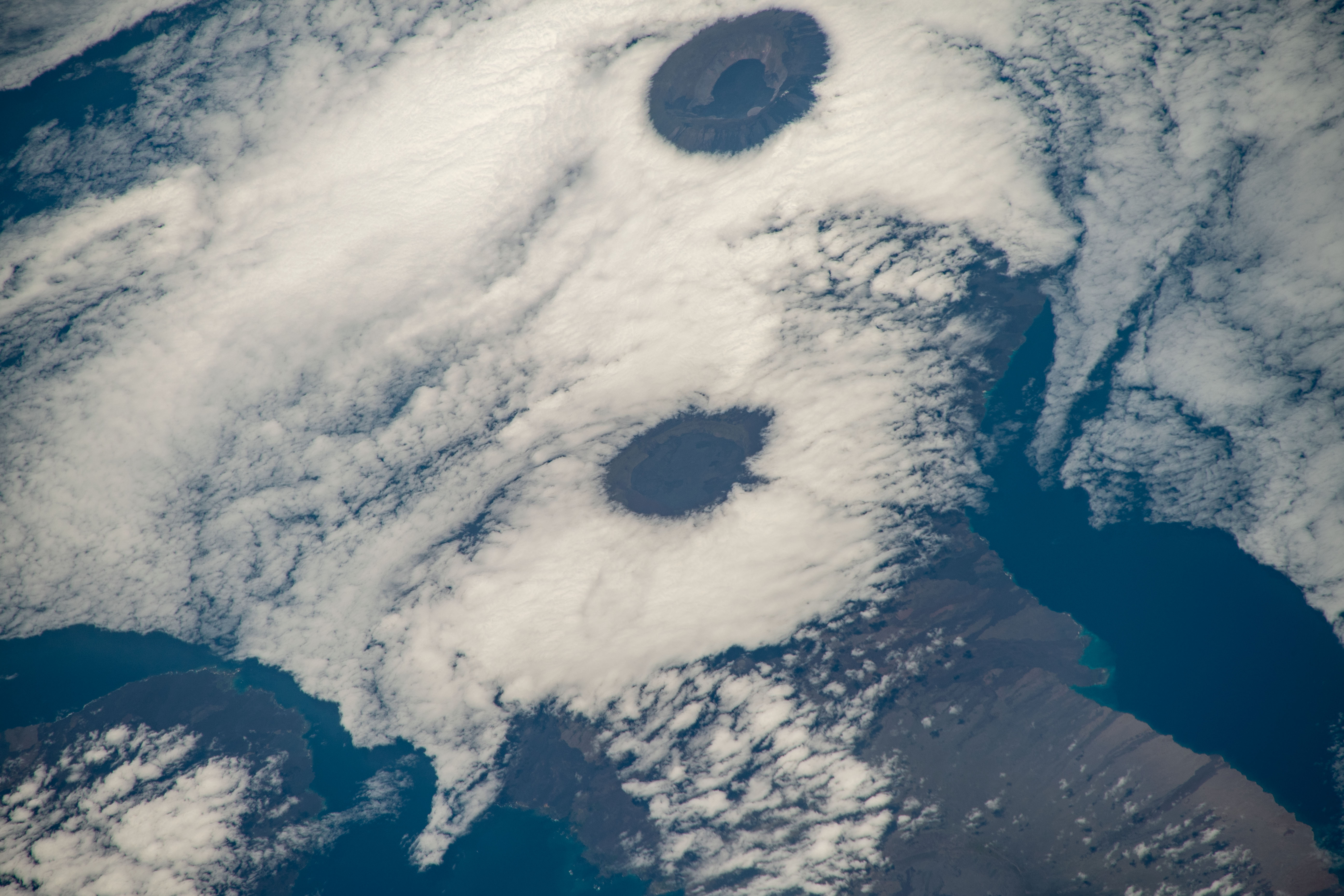 iss068e025399 (Nov. 28, 2022) --- From top, the peaks of Wolf Volcano and Darwin Volcano on Ecuador's Isabel Island, part of the Galapagos Islands, are surrounded by clouds in this photograph from the International Space Station as it orbited 261 miles above the Pacific Ocean.