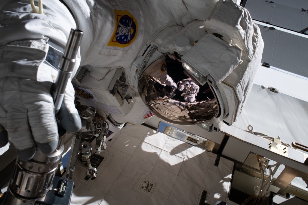The reflection in NASA astronaut Jessica Meir's spacesuit helmet is fellow NASA astronaut Christina Koch photographing her crewmate during a spacewalk to finalize upgrading power systems on the International Space Station's Port-6 truss structure.
