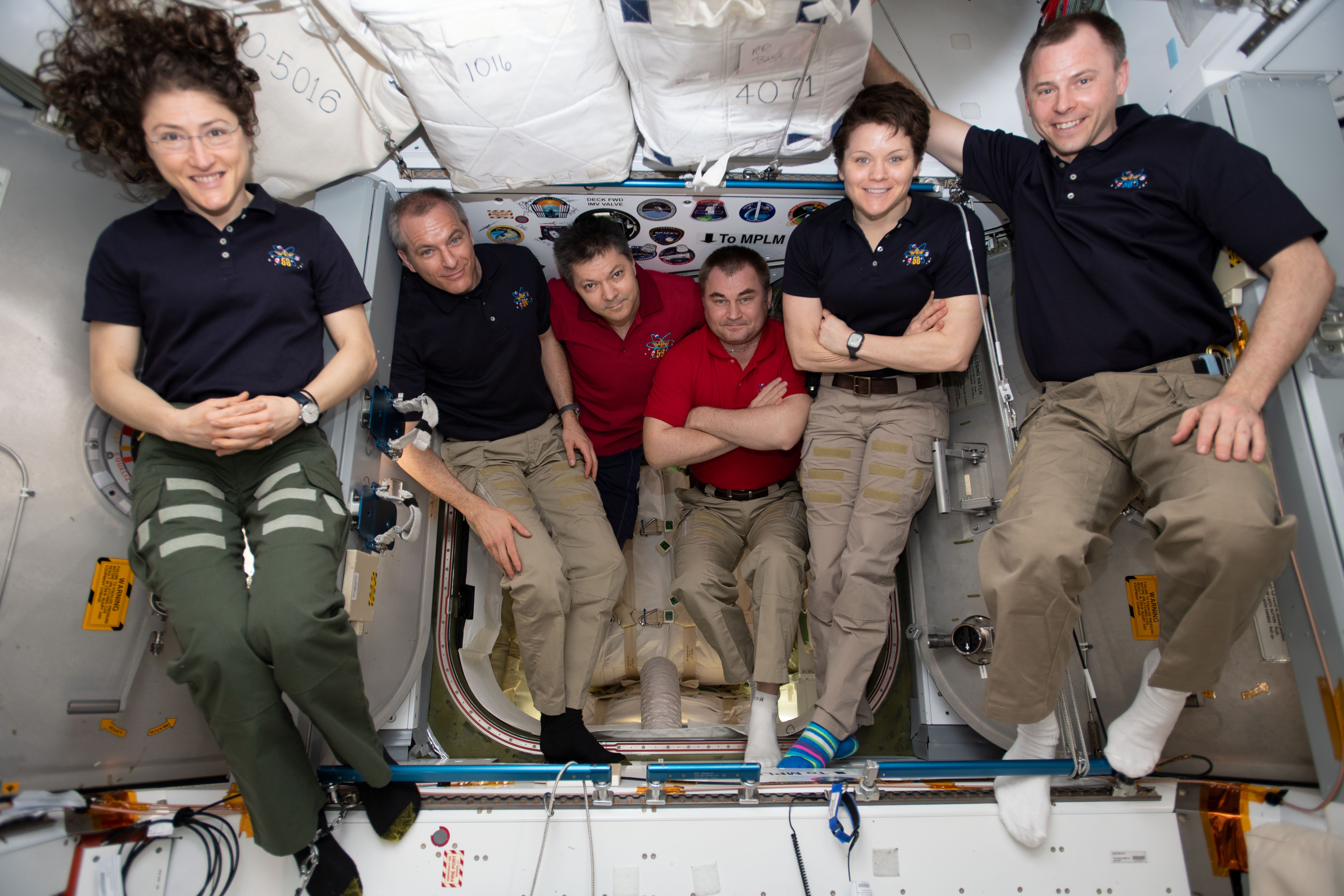 The six-member Expedition 59 crew gathers for a portrait inside of the vestibule between the SpaceX Dragon cargo craft and the Harmony module. The hatch to Dragon was later closed and the resupply ship detached from Harmony before it was released from the grips of the Canadarm2 robotic arm. Dragon spent nearly a month attached to the International Space Station. From left are, astronauts Christina Koch of NASA and David Saint-Jacques of the Canadian Space Agency; Commander Oleg Kononenko and Flight Engineer Alexey Ovchinin of Roscosmos; and NASA astronauts Anne McClain and Nick Hague.