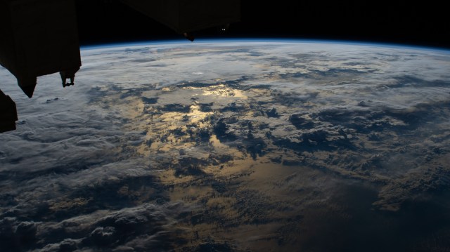 The sun's glint on the Timor Sea between Indonesia and Australia is mellowed by cloud cover in this photograph from the International Space Station.