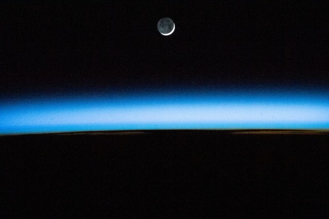 The waxing crescent Moon is pictured above Earth's atmosphere illuminated by an orbital sunset as the International Space Station flew 258 miles above the Atlantic Ocean.