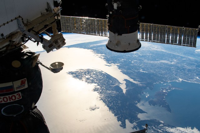 Two Russian spaceships, the Soyuz MS-12 crew ship (left) and the Progress 72 cargo craft, highlight the foreground with the east coasts of the United States and Canada in the background. An Expedition 59 crew member took this photograph as the International Space Station orbited 257 miles above the sun glint-lit North Atlantic Ocean.
