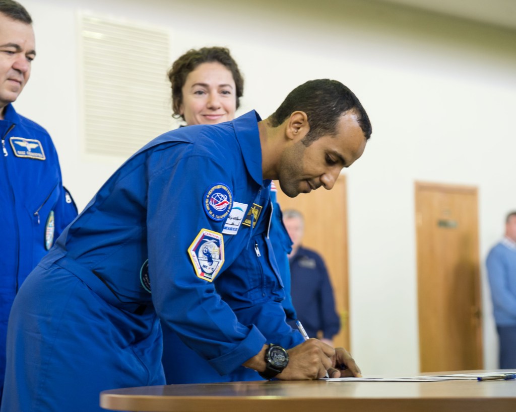 At the Gagarin Cosmonaut Training Center in Star City, Russia, United Arab Emirates spaceflight participant Hazzaa Ali Almansoori signs in Aug. 29 for the first day of qualification exams for flight. Looking on are Expedition 61 crewmembers Oleg Skripochka of Roscosmos and Jessica Meir of NASA. They will launch Sept. 25 from the Baikonur Cosmodrome in Kazakhstan on the Soyuz MS-15 spacecraft for a mission on the International Space Station.