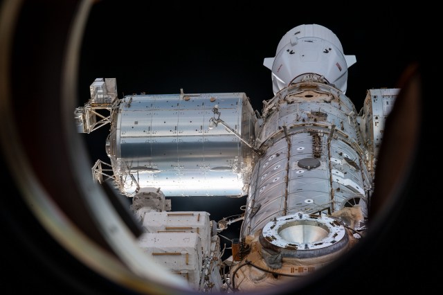 This view of the International Space Station from a window on the orbiting lab's Russian segment shows portions of the Rassvet module's docking port, the U.S. Destiny laboratory module, the Harmony module, Columbus laboratory module, and the Kibo laboratory module. Docked to Harmony at top, is the SpaceX Dragon resupply ship.