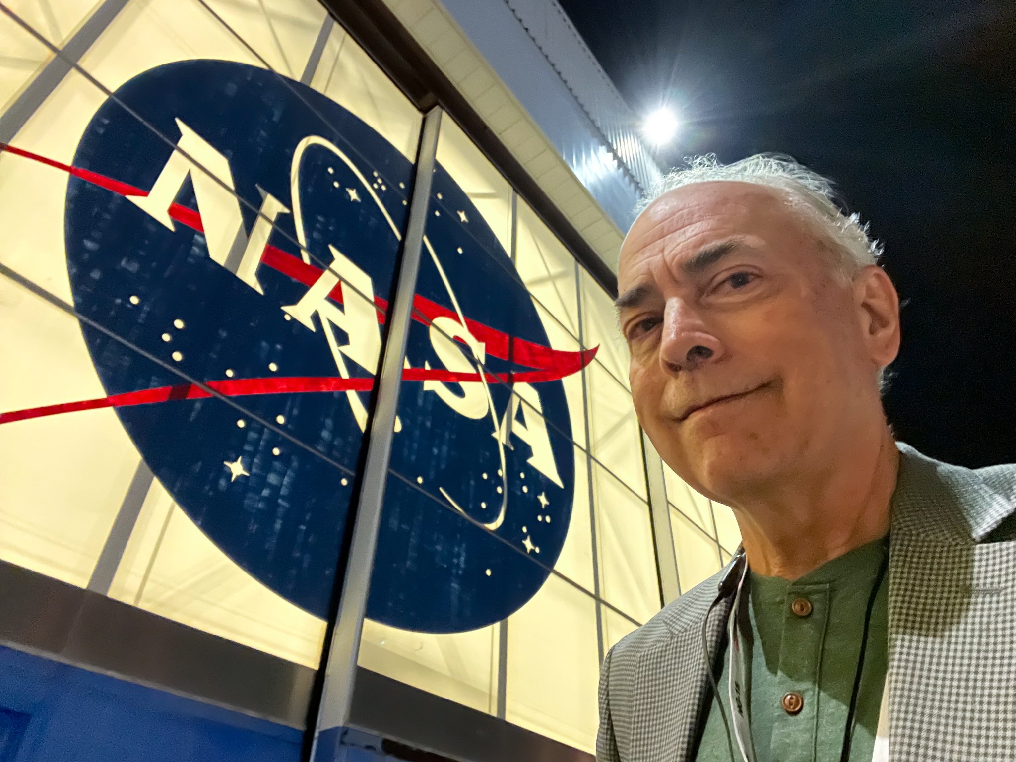 Wade Sisler, executive producer at NASA’s Goddard Space Flight Center in Greenbelt, Maryland, stands in front of a NASA sign