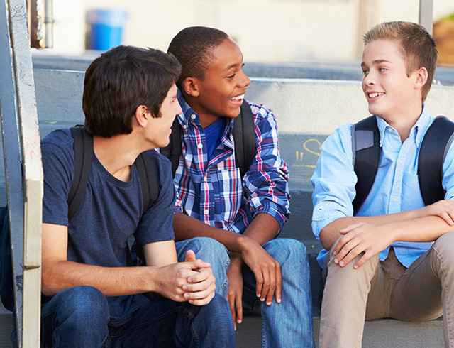 3 students sit on steps and chat with one another
