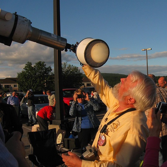 Man looking at solar eclipse through a telescope.
