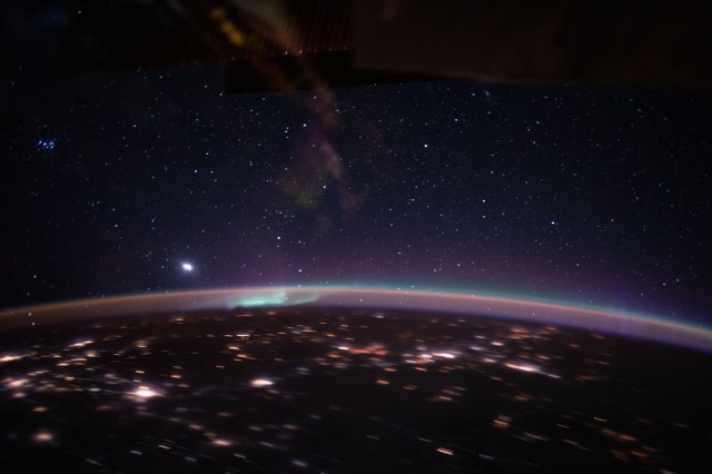 iss062e102390 (March 17, 2020) --- An aurora accents Earth's atmospheric glow underneath a starry sky as the glare from computer instrumentation reflects off a window in the cupola. The International Space Station was orbiting 263 miles above Kazakhstan when an Expedition 62 crewmember took this photograph.