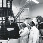 Two men looking at Apollo capsule.