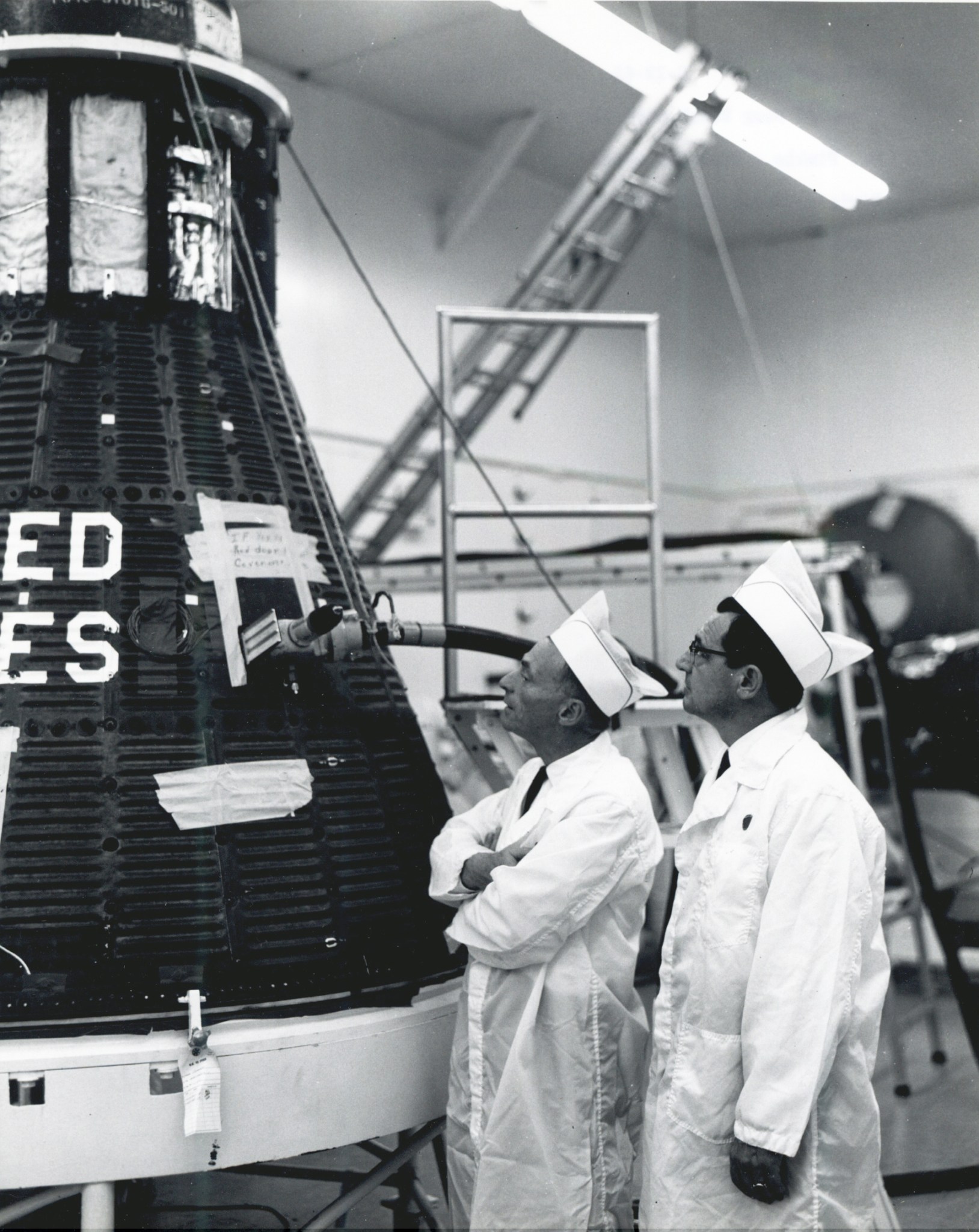 Two men looking at Apollo capsule.