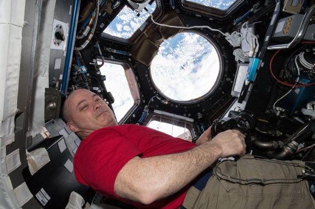Astronaut Scott Tingle watches the SpaceX Dragon cargo craft arrive from inside the seven-windowed Cupola moments before capturing it with the Canadarm2 robotic arm.
