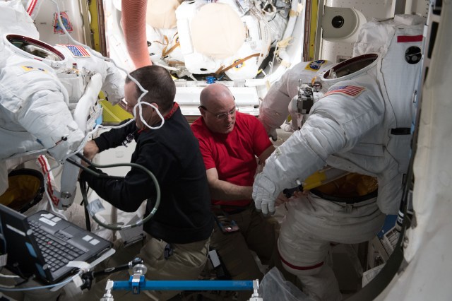 Astronauts Ricky Arnold and Scott Tingle scrub water cooling loops inside a pair of U.S. spacesuits after the completion of spacewalk on March 29, 2018.