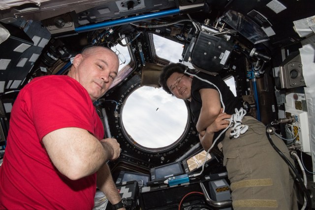 Astronauts Scott Tingle (left) and Norishige Kanai watch the SpaceX Dragon cargo craft arrive from inside the seven-windowed Cupola moments before capturing it with the Canadarm2 robotic arm.